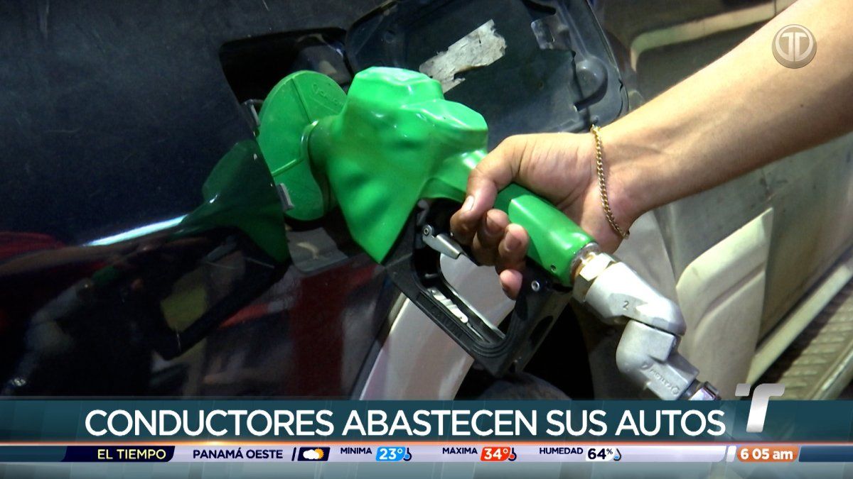 Drivers at a Panama gas station observing price signs after a fuel price increase announcement