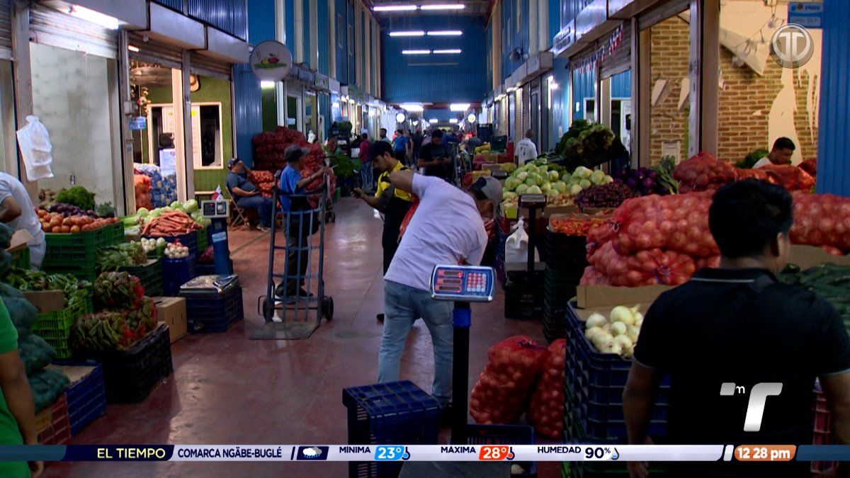 Vendors and produce stalls at Merca Panamá market with delivery truck in the background