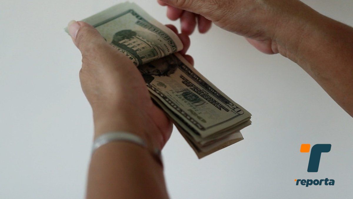 A person receiving cash and checking a smartphone, symbolizing Panama's thirteenth month pay being used for savings and financial planning