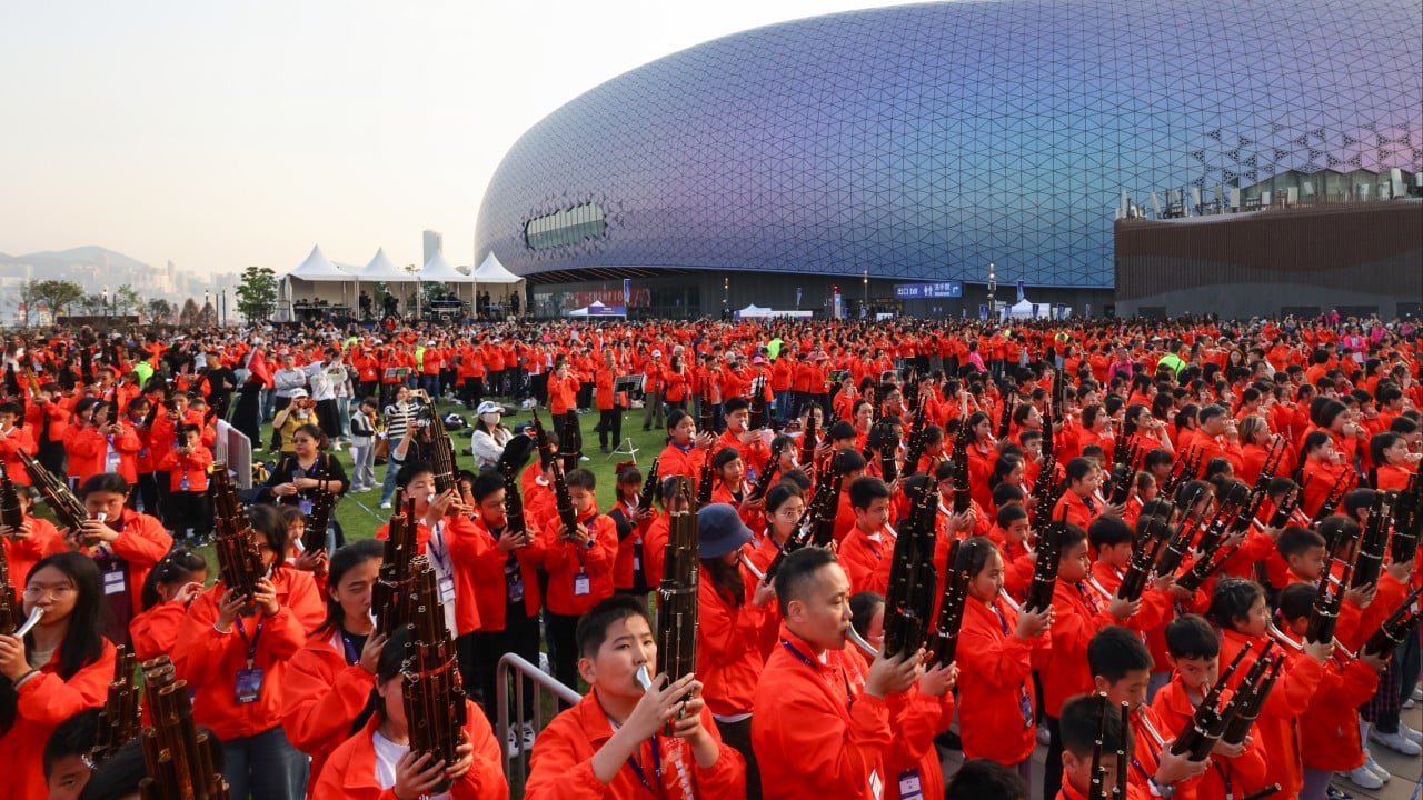 Large group of musicians playing sheng instruments on stage at Kai Tak Sports Park during a record-setting ensemble performance