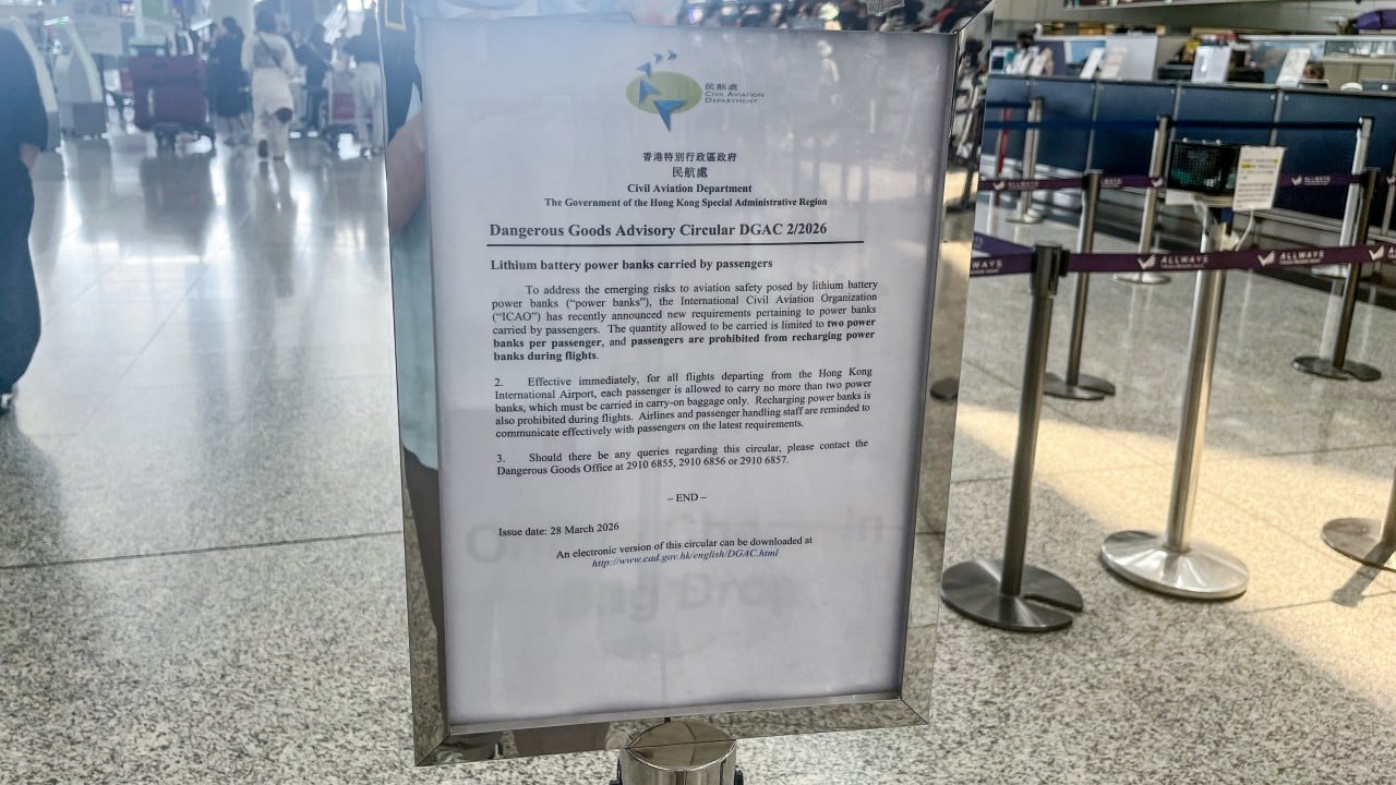 Travelers at an airport security or check-in area near boarding gates with electronic devices and power banks