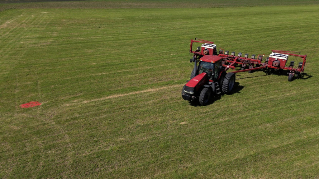 A farm field with fertilizer bags and a tractor, representing concerns about fertilizer availability before spring planting