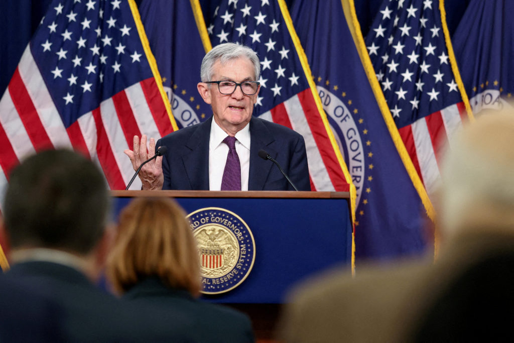 Federal Reserve Chair Jerome Powell speaking at a podium with U.S. flag in the background