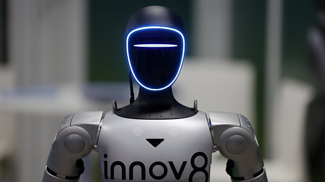 Unitree humanoid and quadruped robots displayed in a factory or showroom with engineers inspecting them