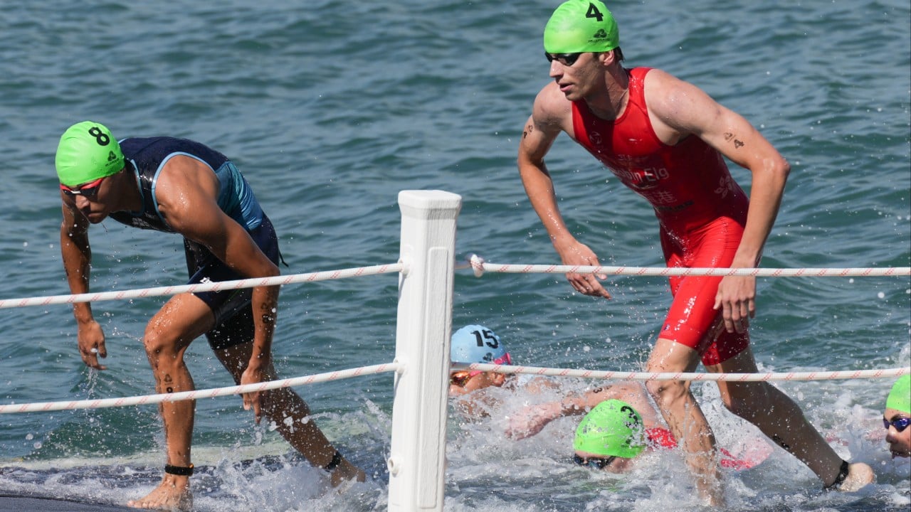 Robin Elg competing in a triathlon swim or bike leg, preparing to withdraw during the Haikou World Triathlon Cup