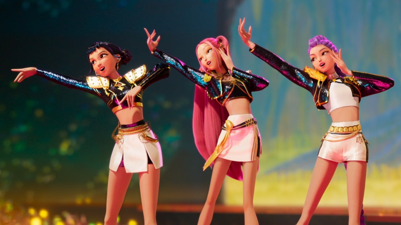 Animated stage shot of three KPop stars from the Demon Hunters film performing amid lights and pyrotechnics