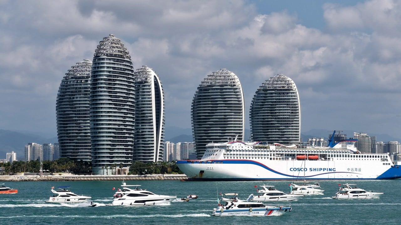 Aerial view of Hainan coastline with port facilities and seaside duty-free shopping area, illustrating the island's free-trade development