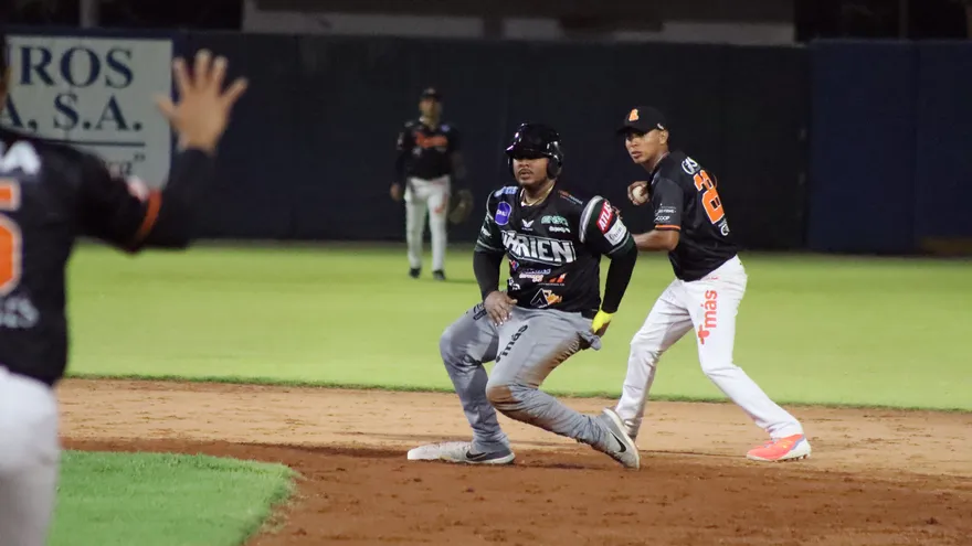 Fans and players at a Panamanian baseball stadium during a national championship game, with a scoreboard and live-streaming cameras visible