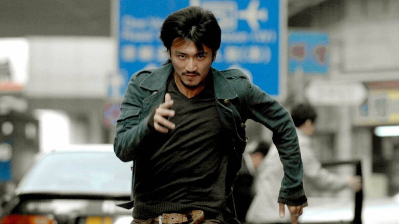 Benny Chan on set directing an action scene, with actors and stunt crew in mid-stunt