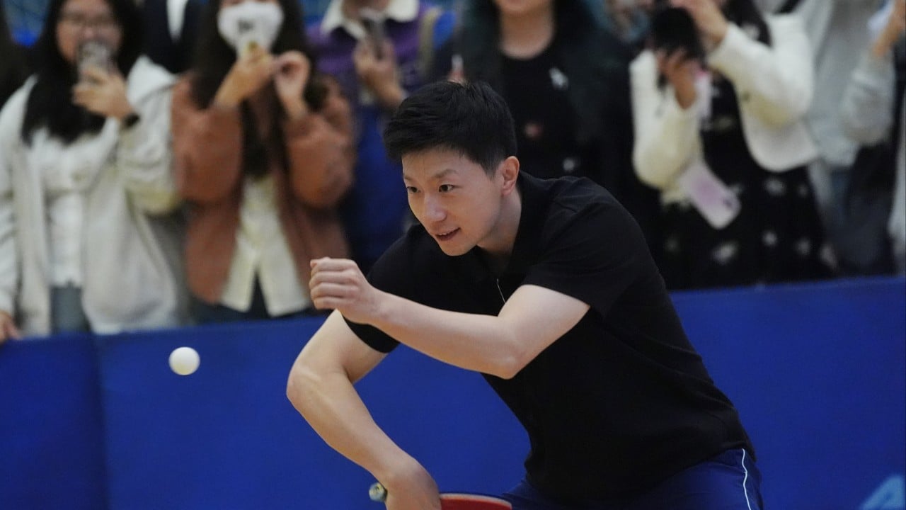 Ma Long at a university sports hall surrounded by students and fans, exchanging shots and signing autographs