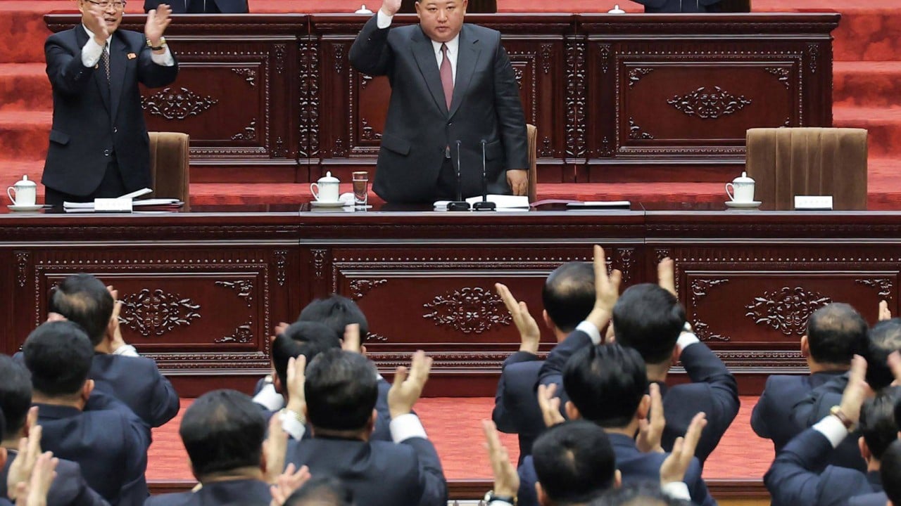 Kim Jong-un speaking at a podium in Pyongyang with North Korean flags and officials in the background