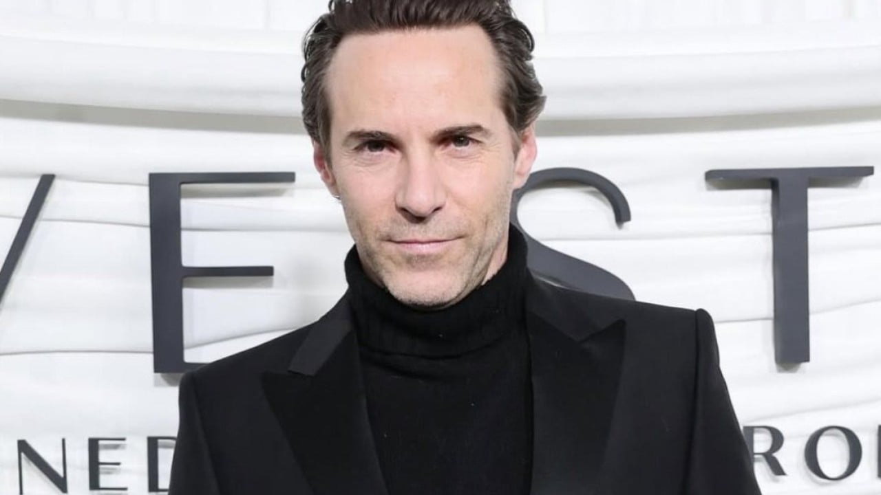 Alessandro Nivola as Calvin Klein on set of Love Story, portraying the designer in period clothing during a dramatic scene
