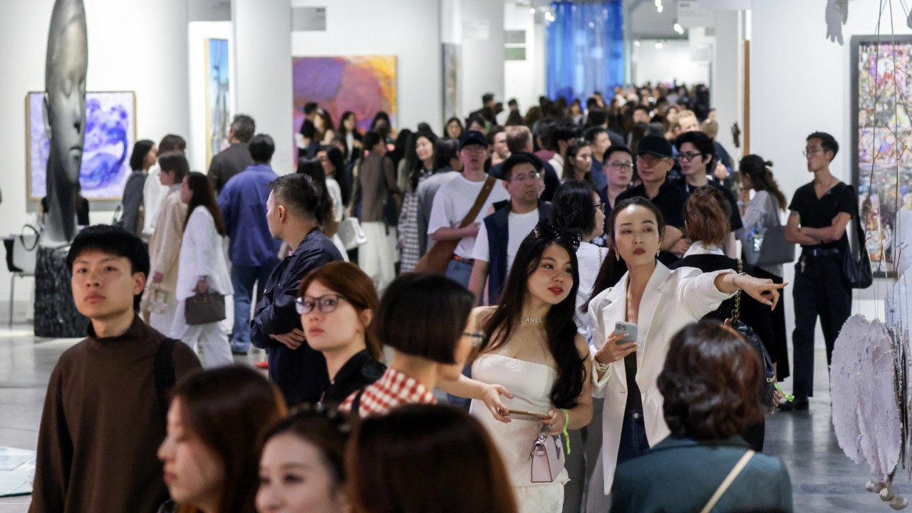 Visitors and galleries at an exhibition booth at Art Basel Hong Kong with artworks on display and people walking through the fair