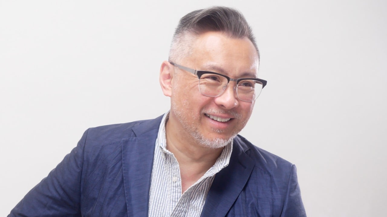 Portrait of couture designer Barney Cheng in a tailoring studio, surrounded by fabrics and finished garments