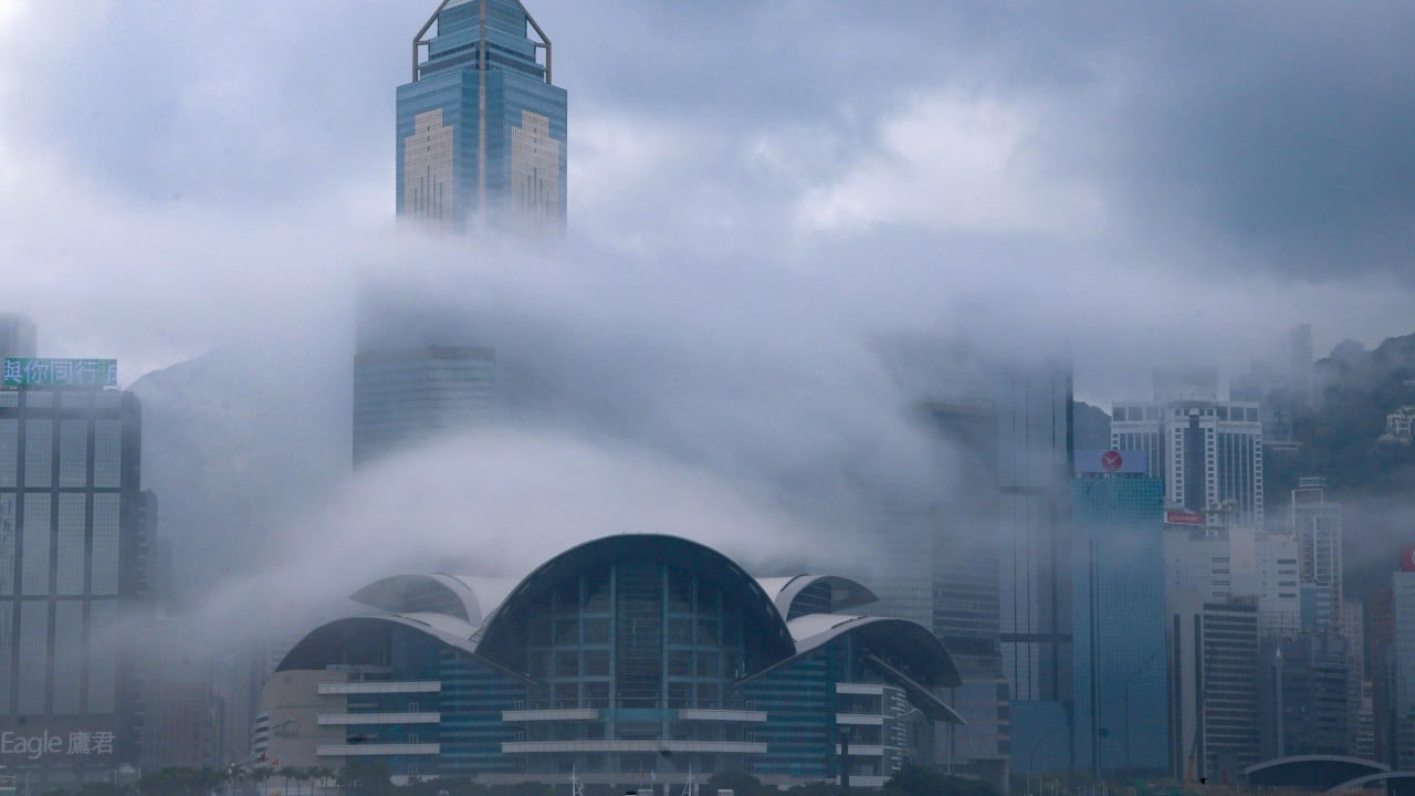 Hong Kong skyline and Victoria Harbour shrouded in low coastal mist and high humidity with low clouds over the city