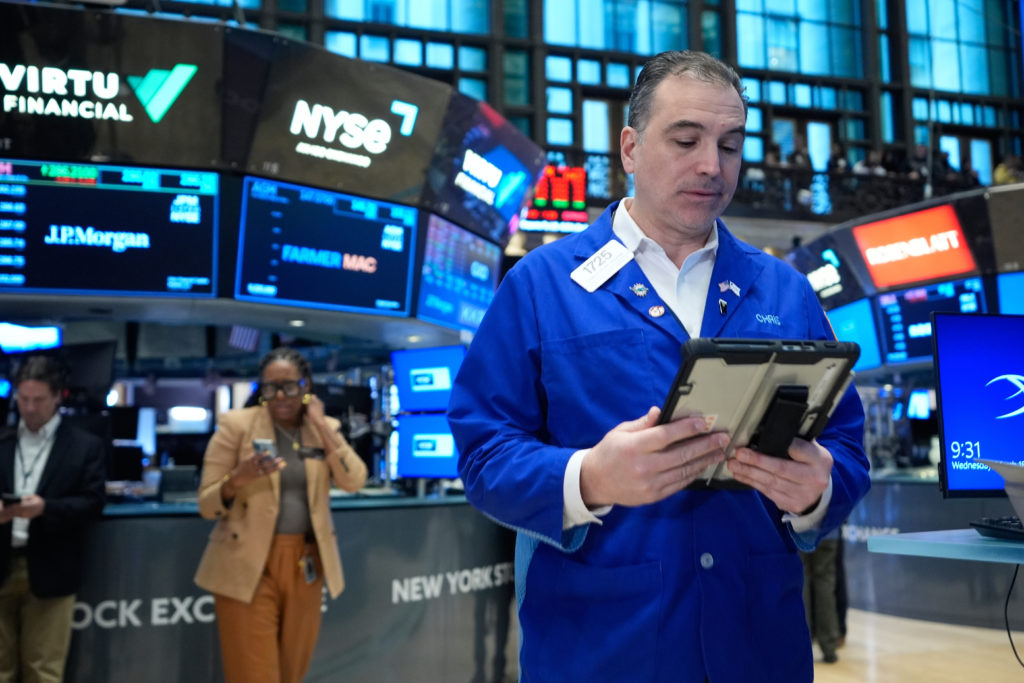 Traders on a U.S. exchange floor with downward market arrows on screens indicating falling stocks