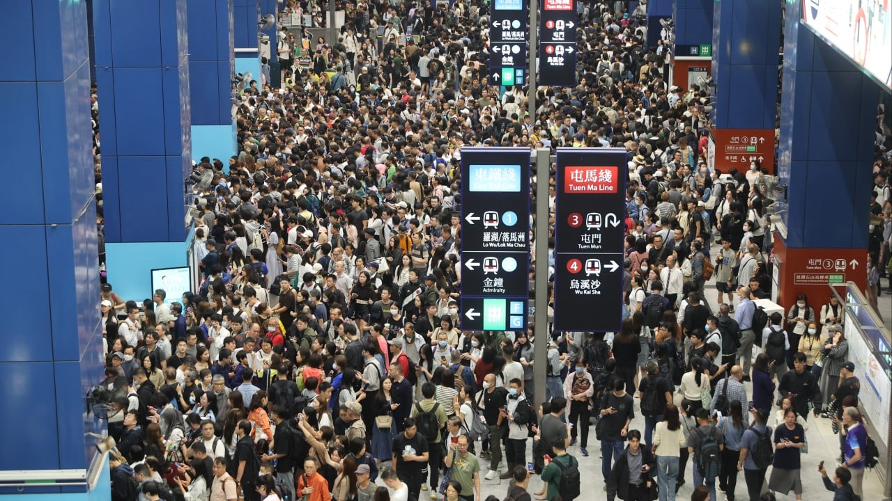 Crowded Hong Kong train platform during rush hour, with commuters waiting after East Rail line service was suspended