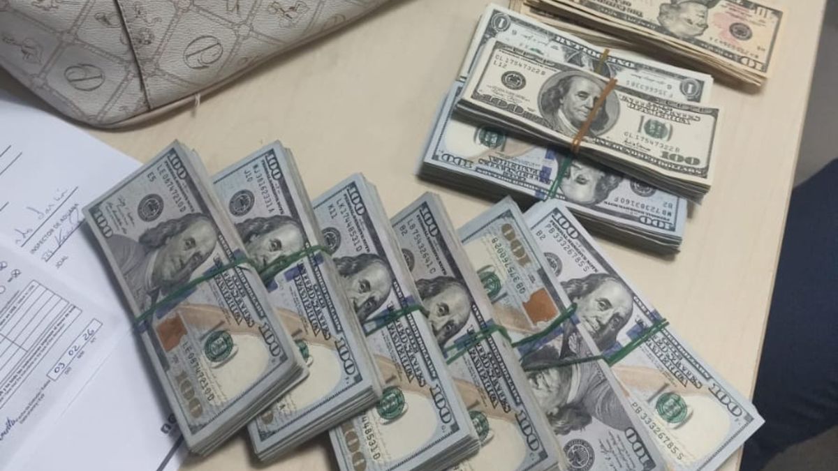 Customs officers at an airport checkpoint inspecting notes of cash seized at Panamá Pacífico