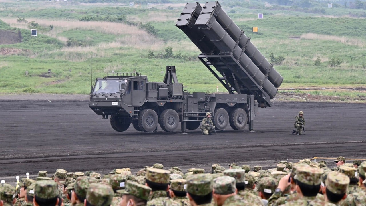 Aerial view of Minamitorishima island with superimposed silhouettes of radar, drones and a missile launcher to illustrate proposed defence deployments