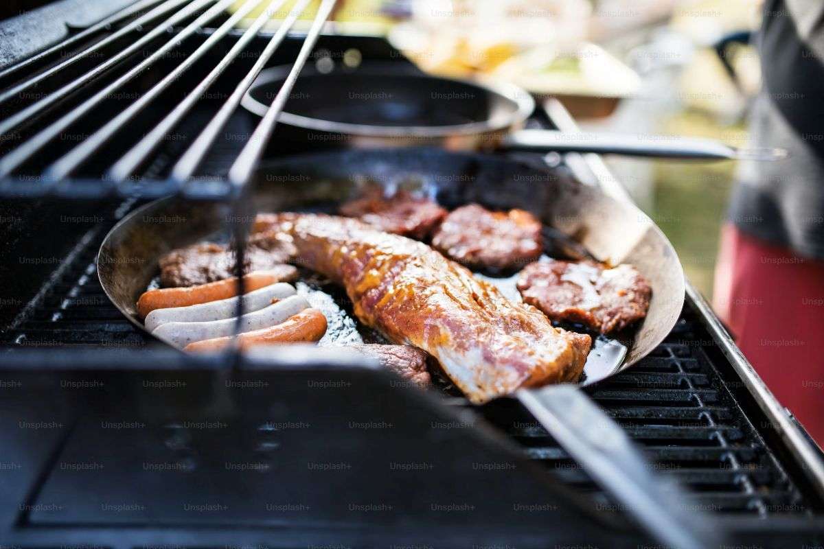 Grilled meats and vendors at Mercado San Felipe Neri during a community BBQ event, with people gathered around stalls and live music onstage