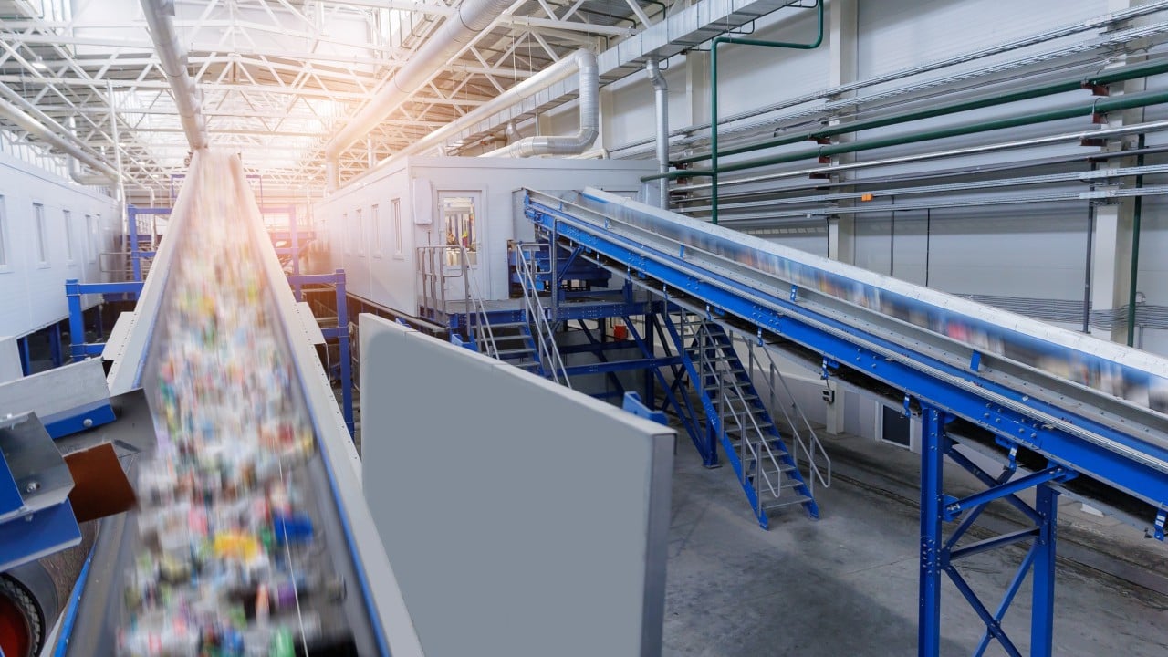 Workers sorting plastic packaging waste in a recycling facility with digital tracking technology in use