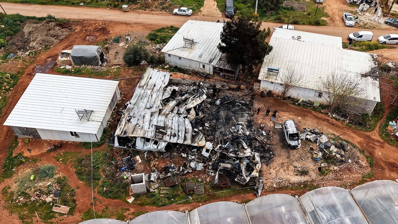 Burned shipping-style containers near Antalya at night with smoke damage and emergency lights in the background