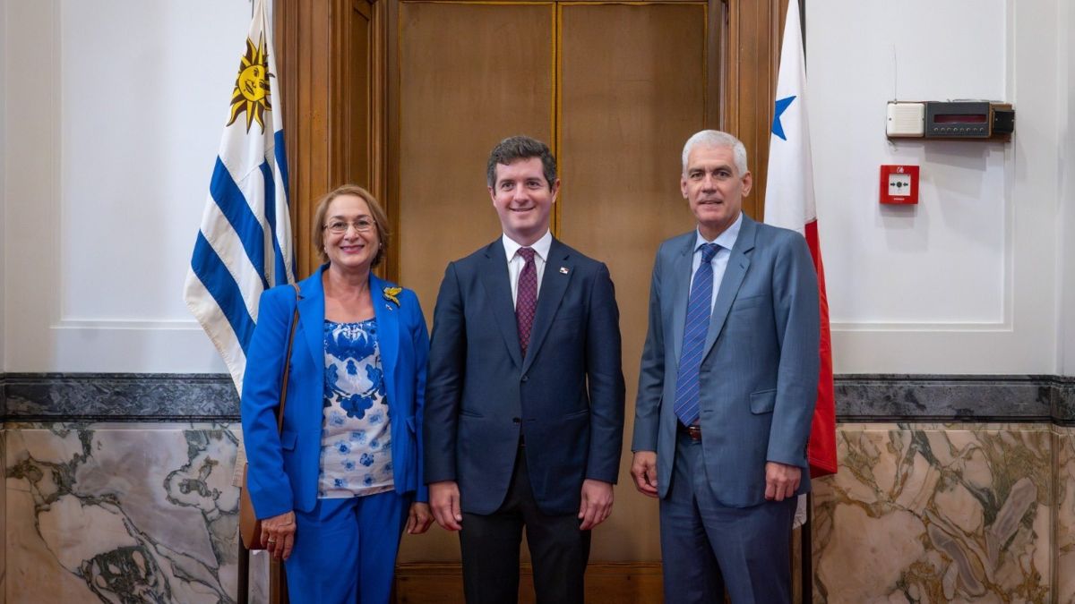 Diplomats from Panama and Uruguay meeting with both countries' flags in the background during a political consultation