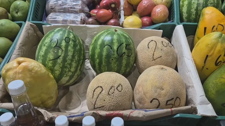 Market stall in La Chorrera with vendors and displays of melons and oranges showing price tags
