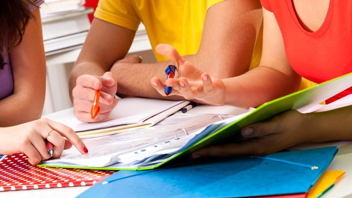 A tutor assisting young students in a classroom setting during a Spanish or math lesson, representing a municipal tutoring program