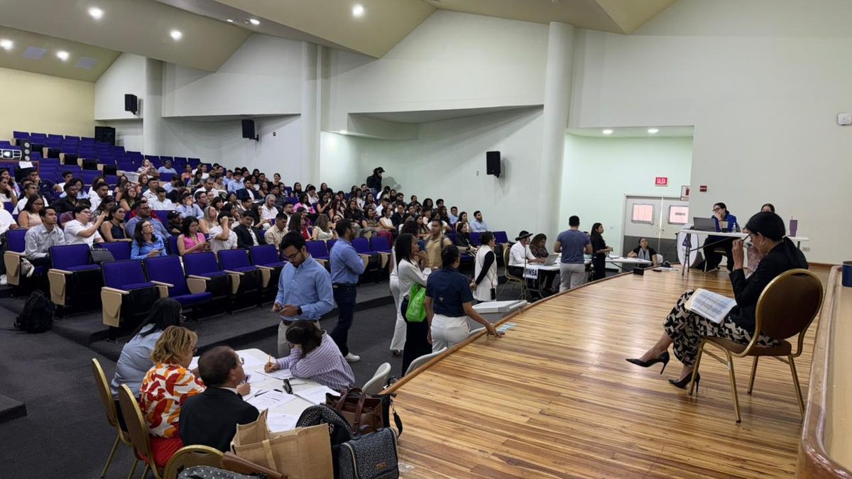 Medical interns in a Panamanian hospital corridor receiving assignments from health officials
