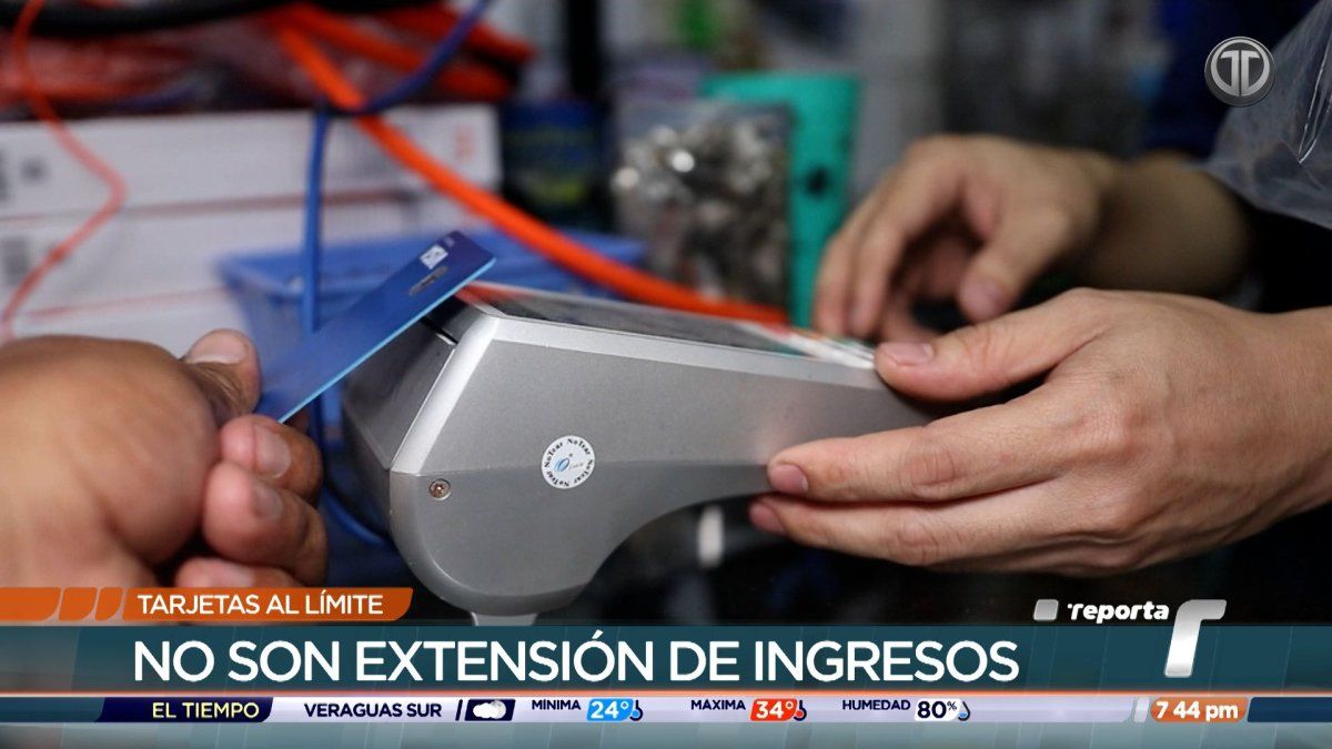 A person holding a credit card and reviewing monthly bills and expenses at a table