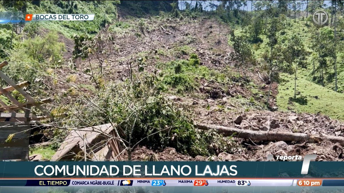 Homes in a hillside community in Bocas del Toro affected by a landslide with muddy earth and damaged ground nearby
