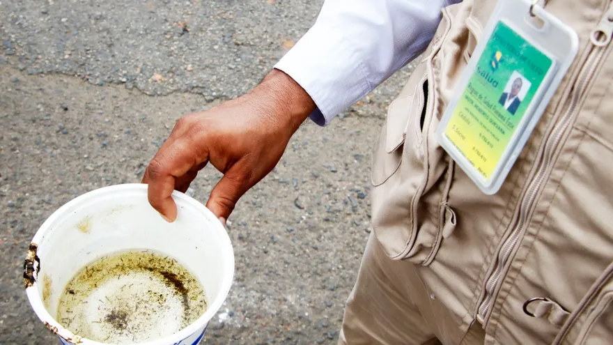 Health workers or residents inspecting standing water containers in a Panamanian neighborhood to prevent dengue mosquitoes