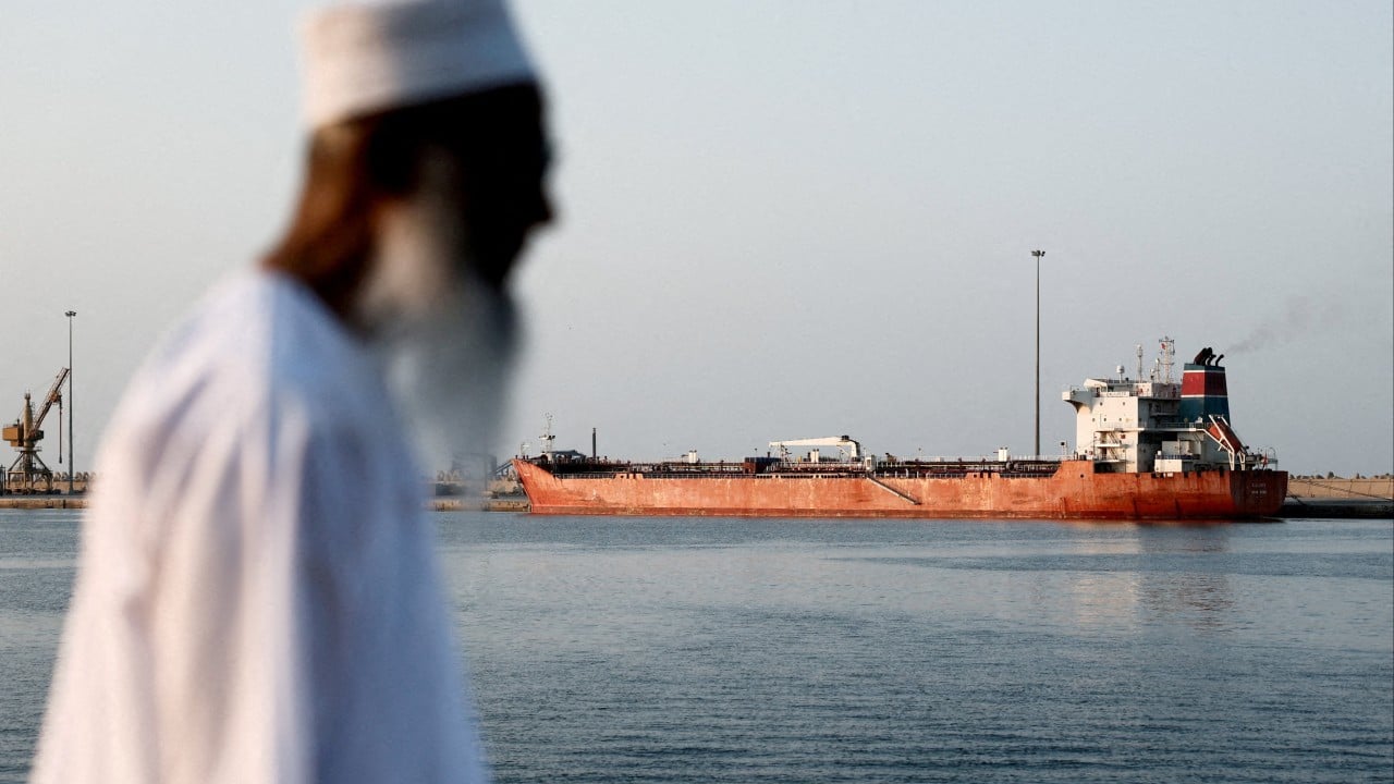 Oil tanker sailing through a narrow maritime strait with a map-style background highlighting the Strait of Hormuz