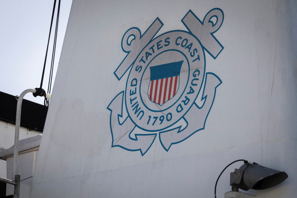 Search and rescue divers inspecting an overturned cargo ship at sea near Japan