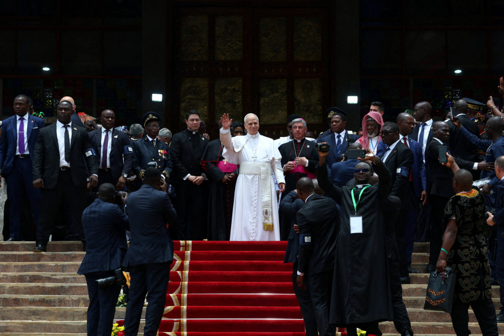 Pope Leo speaking to a crowd during a visit to Bamenda, Cameroon, with supporters gathered around him.