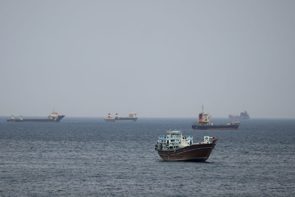 A cargo ship or oil tanker sailing through the Strait of Hormuz under tense regional conditions
