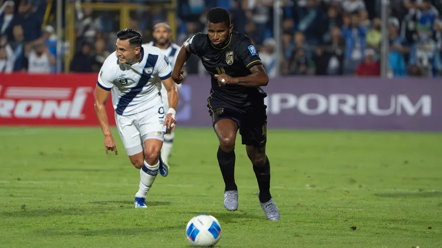 Panama national team players on the field during a football match, with fans and stadium lights in the background