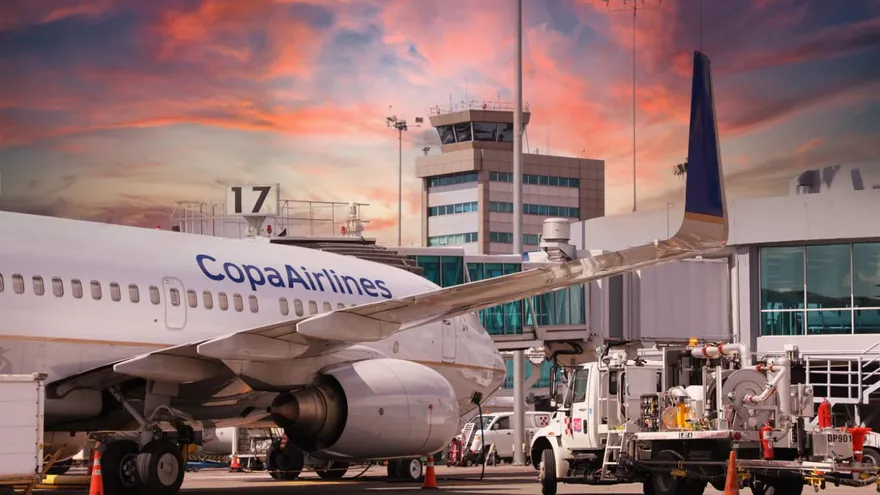 Airplanes parked at a Panama airport terminal with aviation staff and control operations in the background