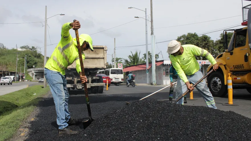 Workers laying asphalt on a Panamanian road as part of sustainable construction using recycled tire materials