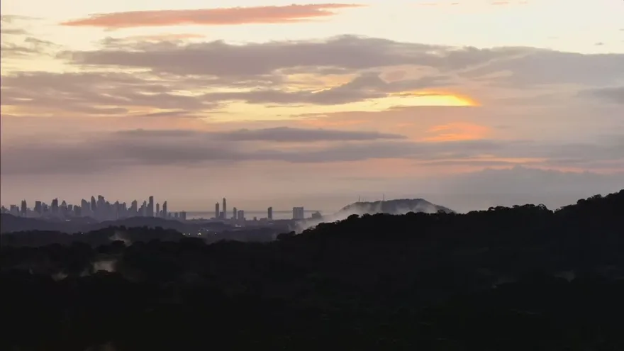 Dark storm clouds and heavy rain over a city street in Panama with people moving quickly under umbrellas