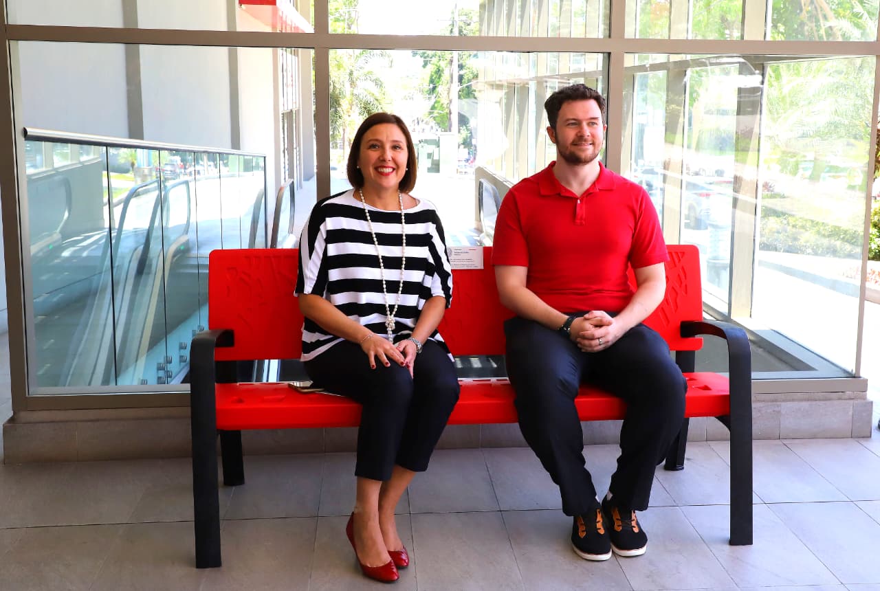 Officials standing near a red bench installed as a symbol against violence toward women in Panama City