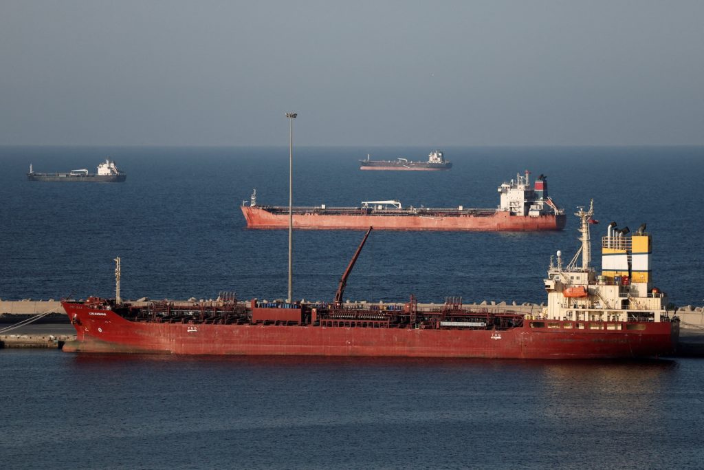 A naval warship patrolling the Strait of Hormuz near commercial tanker traffic