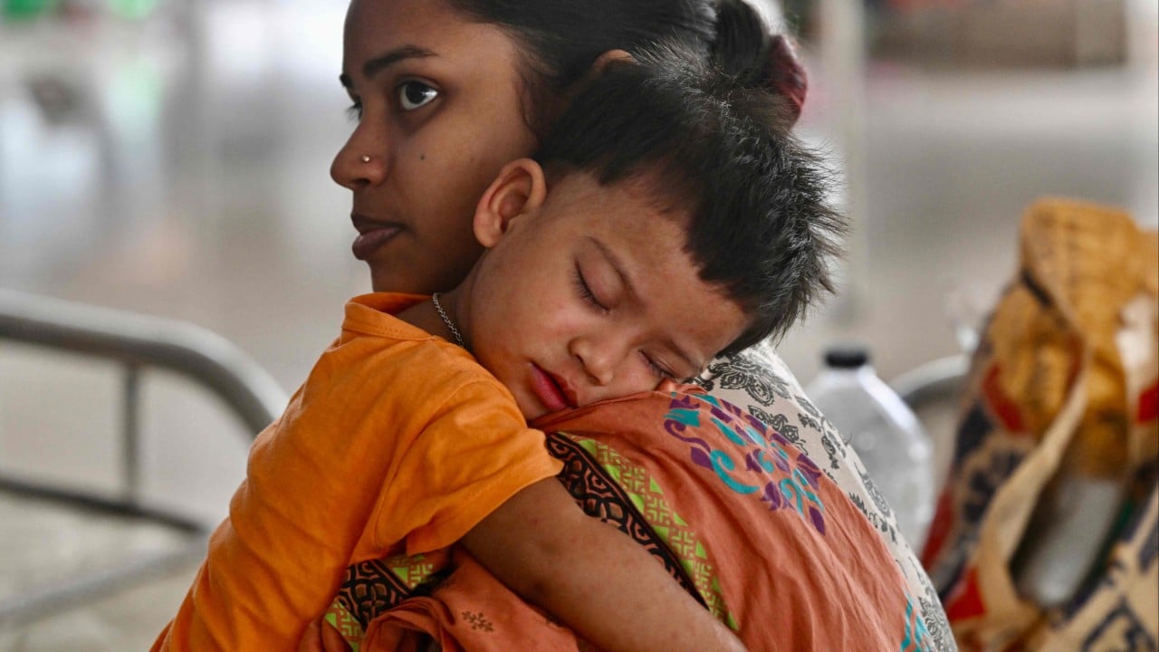 A mother holds a sick child as Bangladesh faces a deadly measles outbreak linked to vaccination gaps