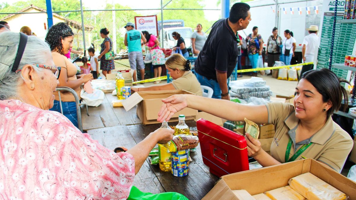 People shopping at an agricultural fair in Panama with fresh food and low-cost produce on display