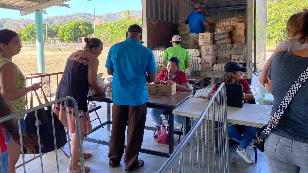 Shoppers at an agro-fair in Panama browsing fresh produce and staple goods at outdoor market stalls