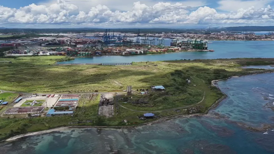 Aerial view of land near the Atlantic entrance of the Panama Canal with industrial and coastal areas in the background
