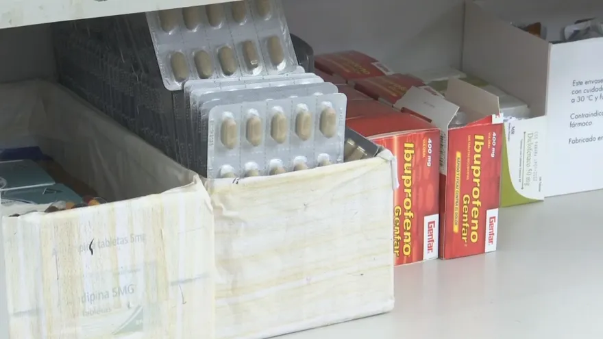 Pharmacist standing behind a pharmacy counter with shelves of medicine boxes in Panama