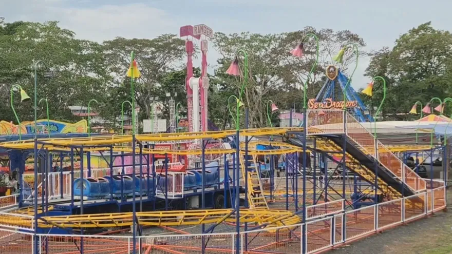 Visitors walking through the Colón Fair with stalls, tents, and festival activity in the background
