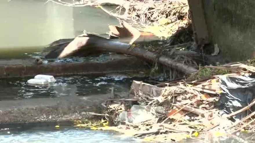 A clogged storm drain filled with grease, gauze, and construction debris blocking water flow in Panama